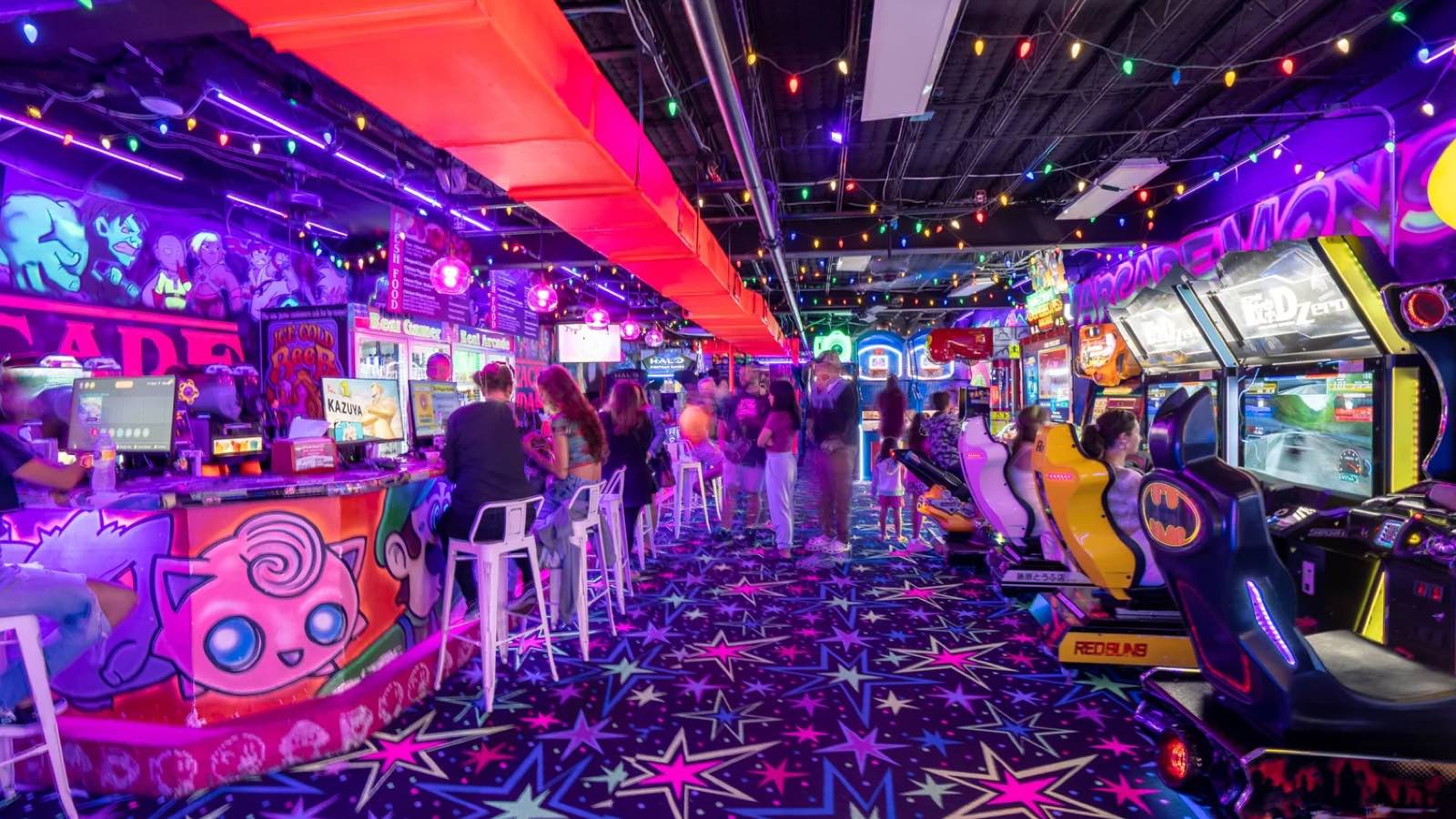 Neon-lit rows of arcade games and racing cabinets at Arcade Monsters in Sarasota
